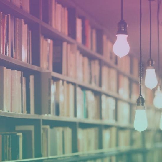 Photograph of a long row of bookshelves with hanging lights.