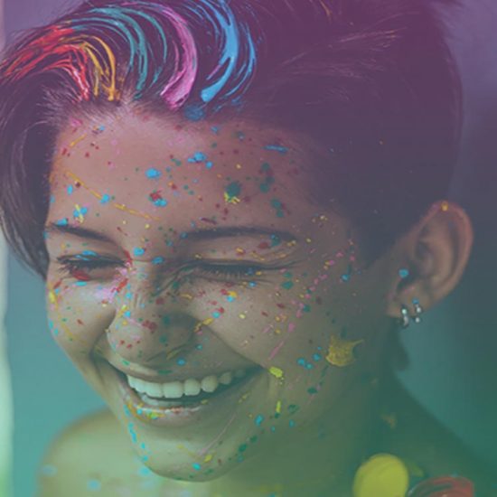 Close up photograph of a person with glitter all over their smiling face.