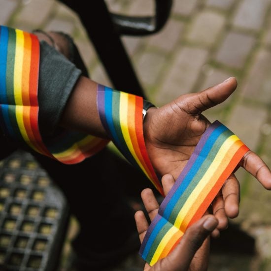 hands holding lgbtqia+ pride ribbon