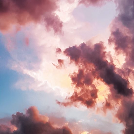 Photograph of pink and purple clouds against a light blue sky.