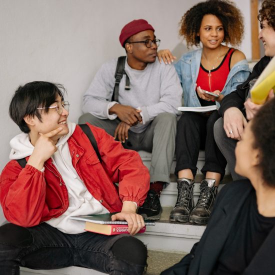 Photograph of a group of students sitting in a stairwell talking.
