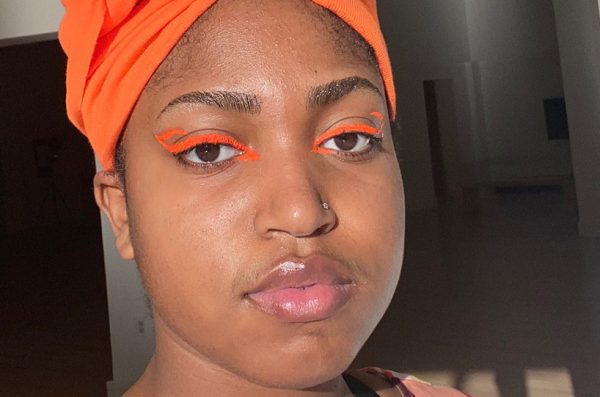 Symphonni with orange eye liner and head wrap.