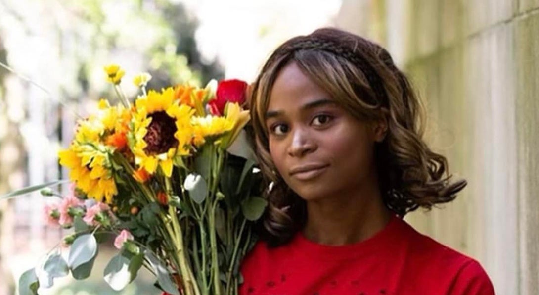 Elise wearing a red t-shirt holding a sunflower bouquet.