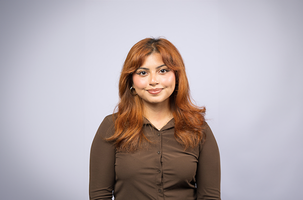 Crystal smiling wearing a brown shirt in front of a white background.